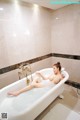 A naked woman laying in a bathtub in a bathroom.