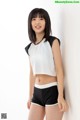 A young woman wearing a white top and black shorts.