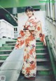 A woman in a kimono standing on a set of stairs.