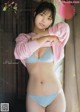 A woman in a pink sweater and blue panties posing for a magazine.