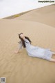 A woman laying on top of a sand dune.