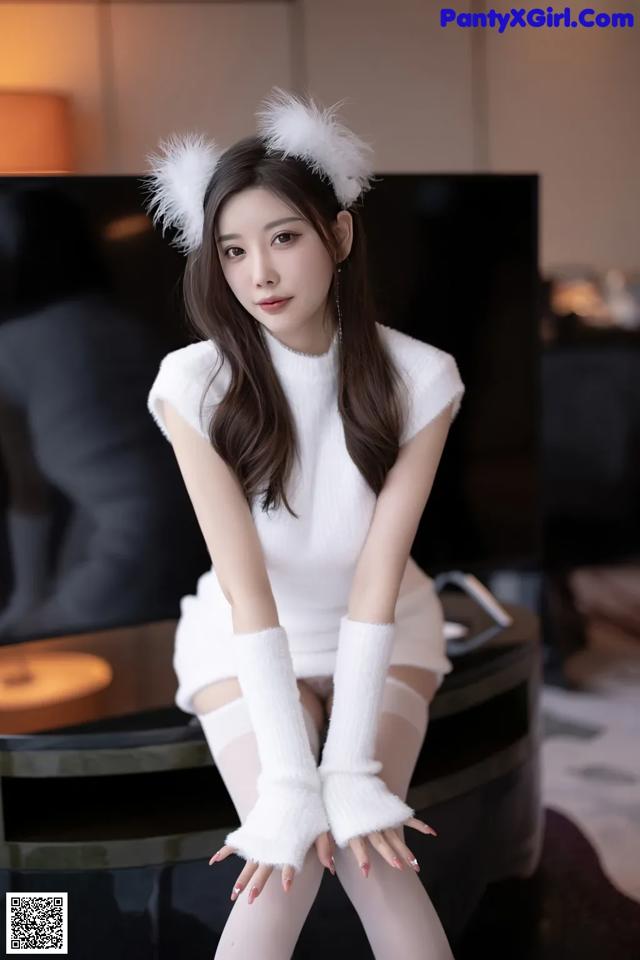 A woman in a white dress sitting on a piano.