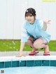 A young woman crouching on the edge of a swimming pool.