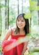 A woman in a red dress sitting in the woods.