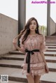 a woman in a pink dress standing on some steps