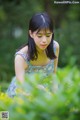 A woman in a blue dress sitting in a field of flowers.