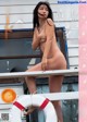 A naked asian woman standing on a boat with a life preserver.