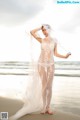 A woman in a wedding dress standing on the beach.