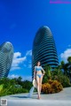 A woman in a blue bikini standing in front of a tall building.