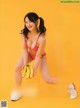 A woman in a red bikini holding a bunch of bananas.