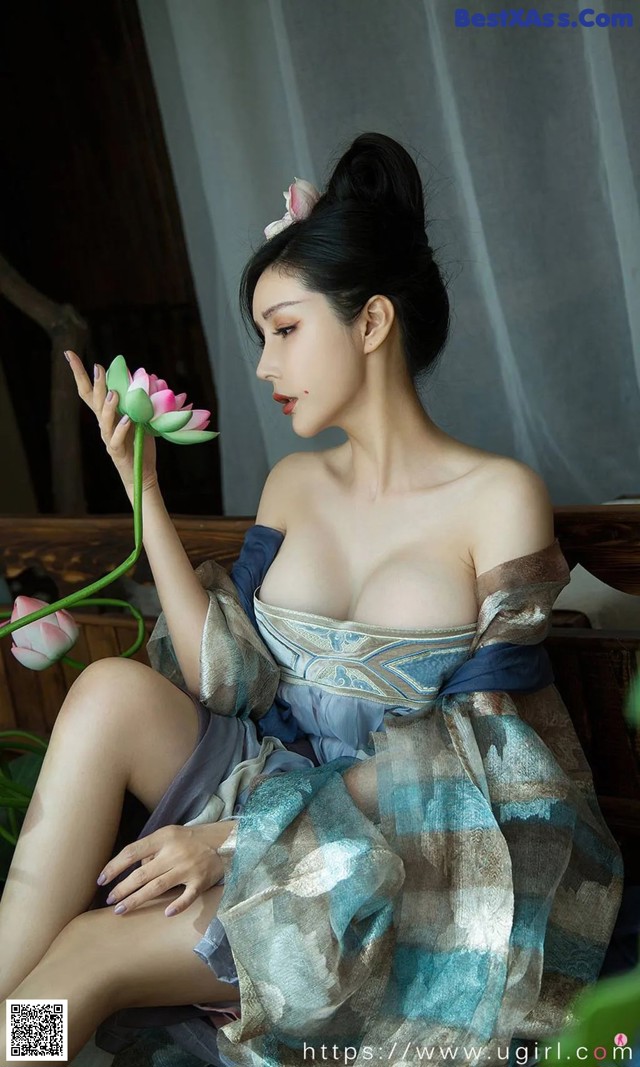 A woman sitting on a bench holding a pink flower.