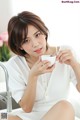 A woman sitting on a sink holding a cup of coffee.