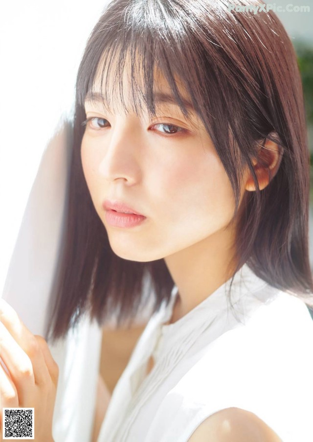 A woman in a white shirt is looking at the camera.