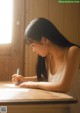 A woman sitting at a table writing on a piece of paper.